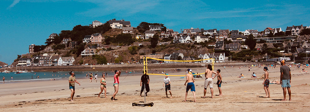 Gruppe macht Yoga am Sandstrand in der Sonne