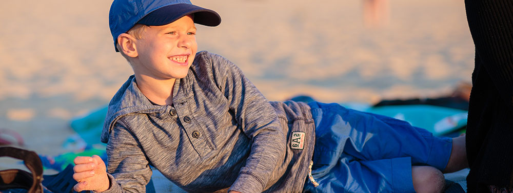 Junge liegt im Sand am Strand in der untergehenden Sonne