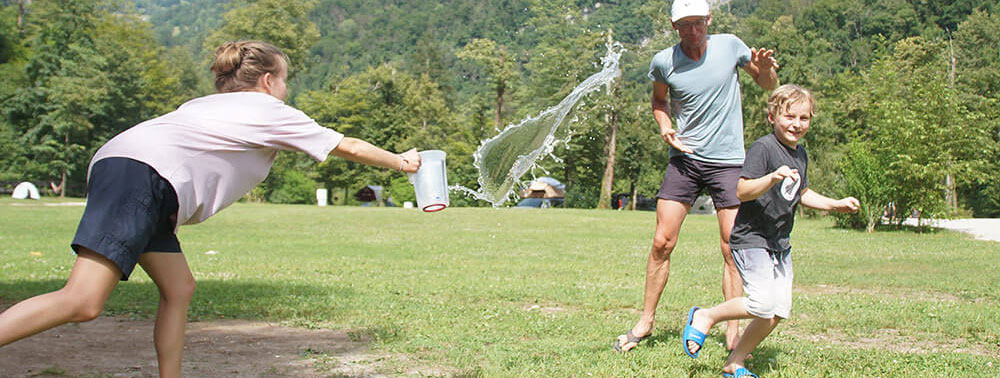 Familie hat eine Wasserschlacht auf einer Sommerwiese